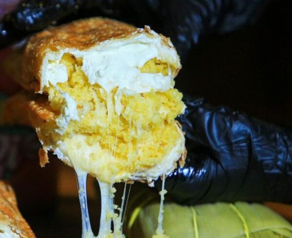 mão de luva segurando pastel de pamonha